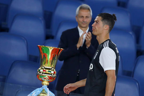 Cristiano Ronaldo walking next to the Coppa Italia trophy