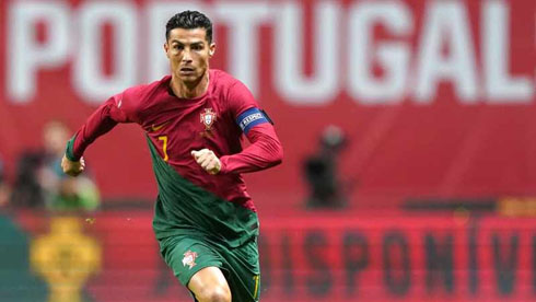 Cristiano Ronaldo running in front of a Portugal banner