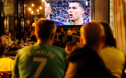 Fans watching Cristiano Ronaldo in a TV screen inside a pub