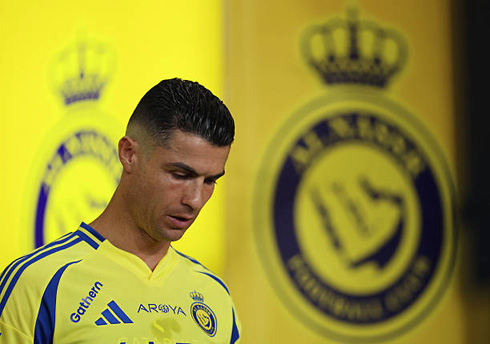 Cristiano Ronaldo with his chin down next to Al Nassr logo