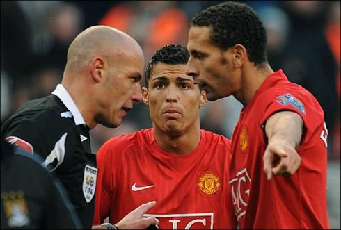 Cristiano Ronaldo making a funny face, while Rio Ferdinand talks to the referee