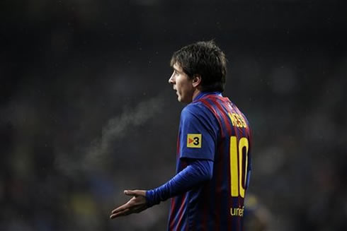 Lionel Messi celebrating a goal while holding Barcelona's shirt badge