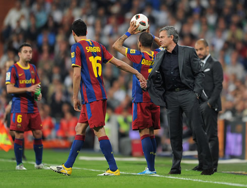 José Mourinho talking to Sergio Busquets, while Xavi and Guardiola observe and Daniel Alves prepares to make a throw-in