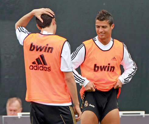 Cristiano Ronaldo pulling up his shorts while smiling and talking to a teammate