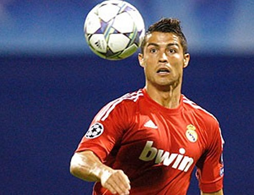 Cristiano Ronaldo looking closely to the ball, as he plays with the Real Madrid new red jersey in the UEFA Champions League
