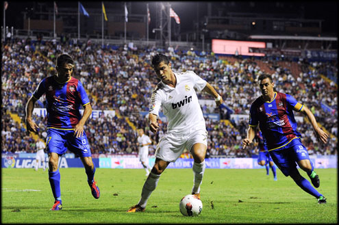 Cristiano Ronaldo dribbling two opponents in La Liga match between Levante and Real Madrid, in 2011-2012