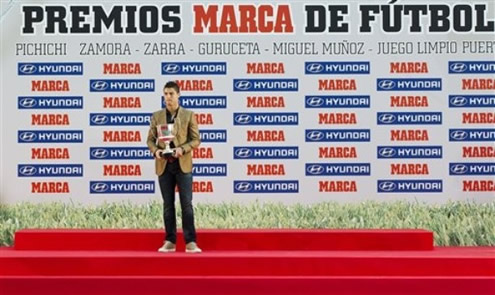 Cristiano Ronaldo standing for a photoshoot while holding Marca's Pichichi trophy from 2010-2011