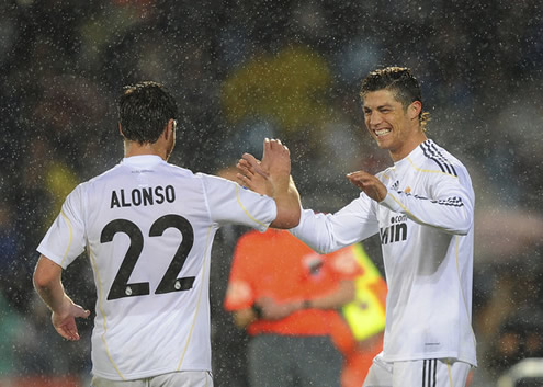 Cristiano Ronaldo smiles just before greeting Xabi Alonso, in a rainy day