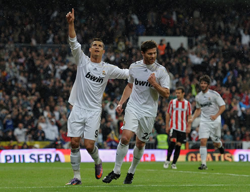 Cristiano Ronaldo with his hand on Xabi Alonso's back, and pointing to the crowd, as he celebrates another goal for Real Madrid