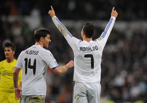 Cristiano Ronaldo stretches his two arms, pointing his fingers to the sky, as he he listens to what Xabi Alonso has to say