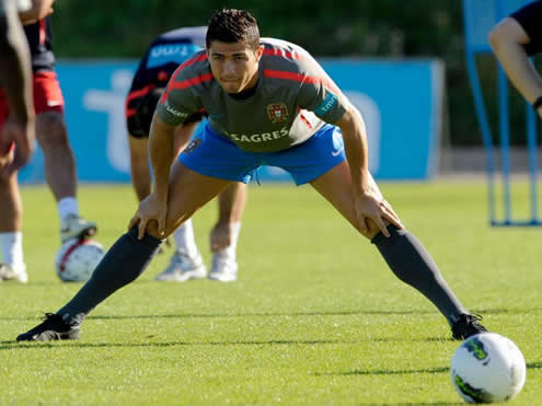 Cristiano Ronaldo stretching with both legs well open, using Nike all-black boots/cleats