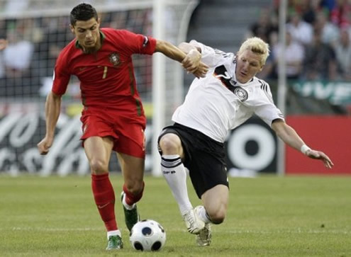 Cristiano Ronaldo running with the ball, while Bastian Schweinsteiger attempts to tackle him