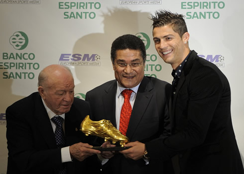 Cristiano Ronaldo taking a photo with Di Stéfano and Eusébio, showing the Golden Boot 2011 award